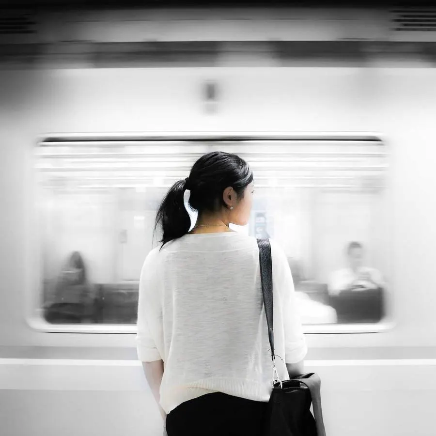 Mulher numa plataforma de trem enquanto o trem passa